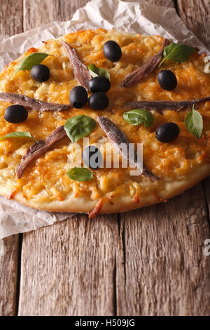 Pizza con alici, olive e cipolla vicino sul tavolo. In verticale Foto Stock