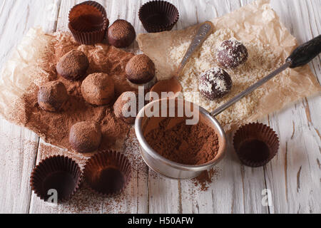 Spargendo tartufi di cioccolato il cacao in polvere e i dadi da vicino sul tavolo. Posizione orizzontale Foto Stock