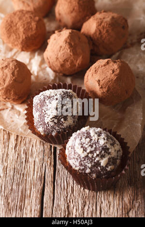 Tartufi di cioccolato su un foglio di carta di close-up su una tavola di legno verticale. Foto Stock