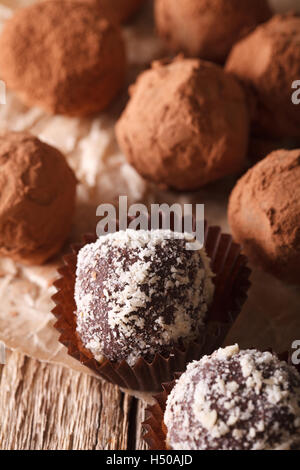 Tartufi di cioccolato nel cacao e dadi macro su un tavolo di legno. In verticale Foto Stock