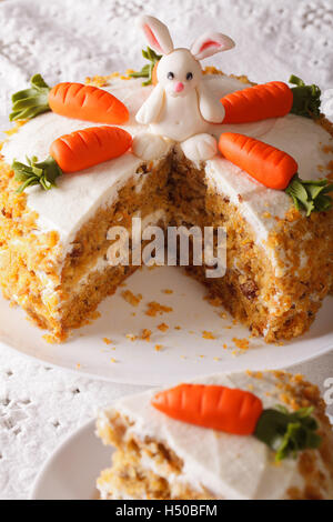 Torta di carote decorate con bunny e slice vicino sul piano verticale. Foto Stock