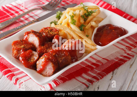 Salsiccia Currywurst con patatine fritte close-up su una piastra. Posizione orizzontale Foto Stock