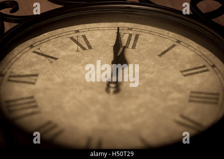 Orologio antico mostra minuto a mezzanotte con la deliberata focus sul numero romano 12 e la profondità di campo del resto fo Foto Stock