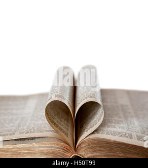 Una vecchia Bibbia aperta con la deliberata concentrarsi sui bordi del a forma di cuore le pagine ripiegate e copia di spazio. Profondità di campo. Foto Stock