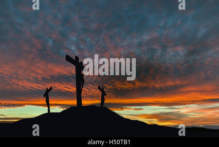 Una silhouette della crocifissione di Gesù Cristo sulla croce con altri 2 Briganti contro un tramonto spettacolare. Foto Stock