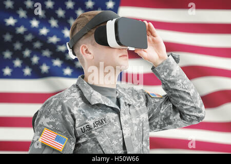 In ambienti chiusi shot del soldato USA indossare occhiali per realtà virtuale con bandiera americana sullo sfondo Foto Stock