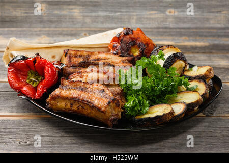 La carne e le verdure arrostite su una griglia con verdi la piastra nera nello stile rustico Foto Stock