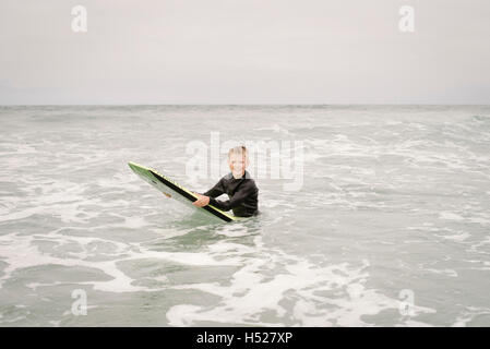 Ragazzo biondo bodyboarding nell'oceano. Foto Stock