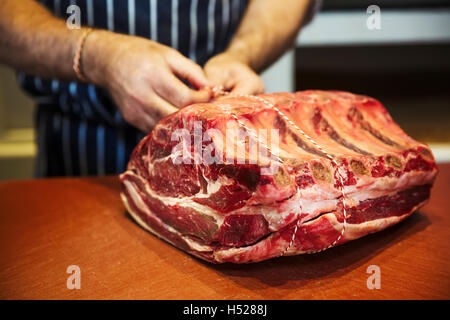 Butcher preparare un grande pezzo di carne di manzo in un butcherer's shop. Foto Stock