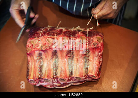 Butcher preparare un grande pezzo di carne di manzo in un butcherer's shop. Foto Stock