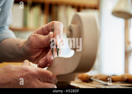 Un liutaio lavorando nella sua officina, utilizzando gli strumenti a mano a forma di scalpello e il ricciolo di scorrimento il violino stock. Foto Stock