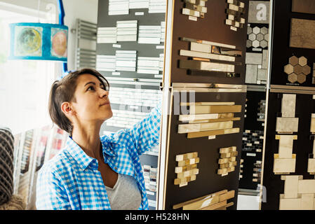 Donna che guarda la merce in interior design store. Infissi e arredi, campioni di piastrella, Foto Stock