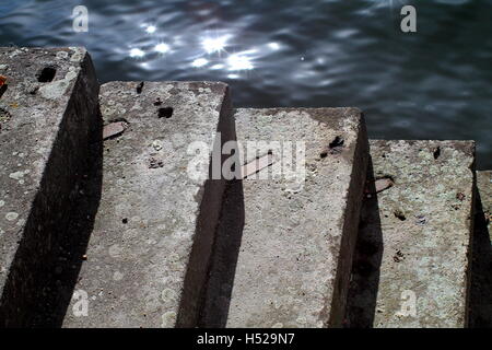 Vecchia scalinata di concreti passi sul waterside con lightspots. Foto Stock