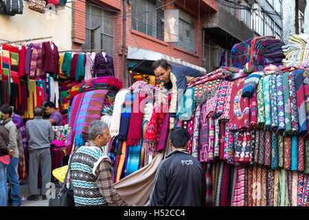 Kathmandu, Nepal - Ottobre 19, 2014: un venditore mostra sciarpe ai clienti sul mercato nel quartiere Thamel Foto Stock