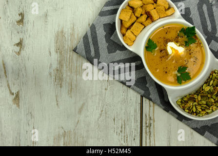 Piatto bianco con zuppa di zucca, semi di zucca e piccole, al forno i crostini di pane preparato di foglie fresche di prezzemolo e una crema Foto Stock