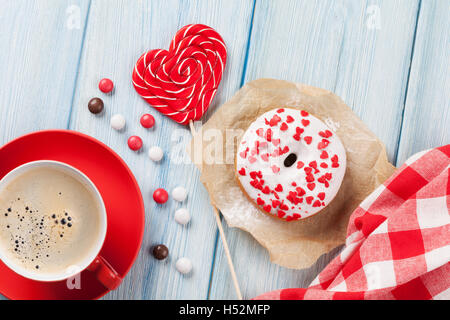 Ciambella, a forma di cuore ad candy e caffè sul tavolo di legno. Vista superiore Foto Stock