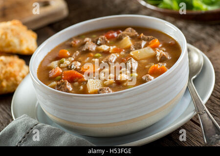 Una ciotola di deliziose carni bovine e la zuppa di farro con carote, pomodoro, patata, il sedano e i piselli. Foto Stock