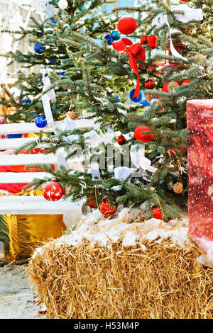 Addobbi per l'albero di Natale, regali, banco, fieno all'esterno. Foto Stock