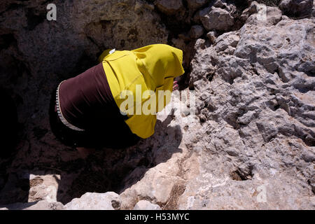 Un elemento femmina del samaritano setta pregando su una roccia-affondato trincea chiamato 'Issac altare' sul monte santo di garizim il luogo dove secondo la tradizione Abramo offrì Isacco nella West Bank vicino alla città di Nablus, Israele il 18 ottobre 2016. I samaritani che fanno risalire le proprie radici del regno settentrionale di Israele in che cosa ora è la Cisgiordania settentrionale riguardo il monte di garizim piuttosto che Gerusalemme il Monte del Tempio, come è stato il luogo scelto da Dio per un tempio santo. La montagna continua ad essere il centro del samaritano la religione per questo giorno e oltre il 90 per cento di tutto il mondo Foto Stock