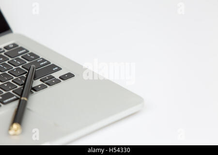 La penna nera che giace sulla parte superiore di un laptop. studio shot su sfondo bianco Foto Stock