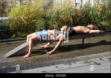 Coppia giovane a prendere il sole in una calda giornata sulla linea alta Park di New York City Foto Stock