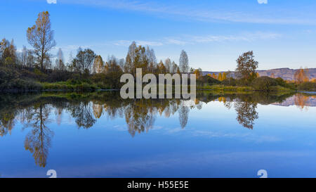 Paesaggio fluviale con multicolore di caduta di alberi. Caduta idilliaco paesaggio fluviale. Bella giornata autunnale sul tranquillo fiume. Foto Stock