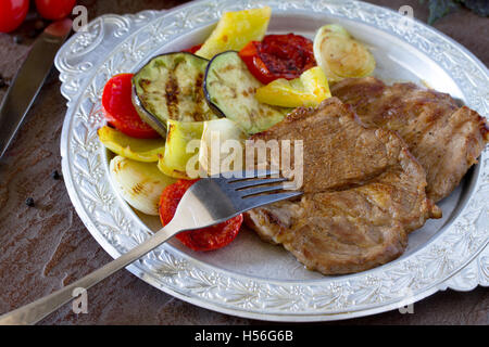 Bistecca alla griglia la carne di maiale e verdure alla griglia su pietra marrone dello sfondo. Foto Stock