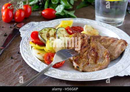 Bistecca alla griglia la carne di maiale e verdure alla griglia su pietra marrone dello sfondo. Foto Stock