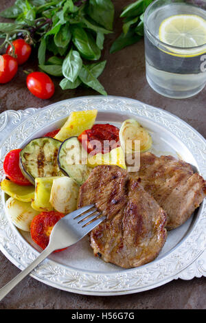 Bistecca alla griglia la carne di maiale e verdure alla griglia su pietra marrone dello sfondo. Foto Stock