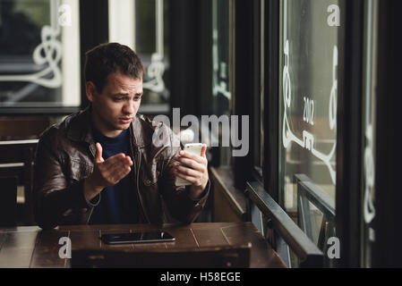 Giovane uomo facendo una chiamata video dal suo telefono cellulare. Messa a fuoco selettiva. Foto Stock