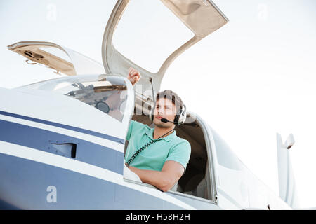 Ritratto di fiducioso giovane pilota in piccolo aereo Foto Stock