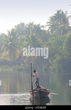 Un anziano pescatore locale sterline la sua piccola barca attraverso il Kerala backwaters vicino Koch nell India meridionale all'alba Foto Stock