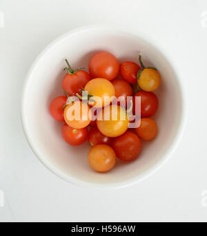 Ultimo pomodori ciliegia della stagione nella piccola rotonda ciotola bianco su sfondo bianco. Semplice vita ancora in formato quadrato. Foto Stock