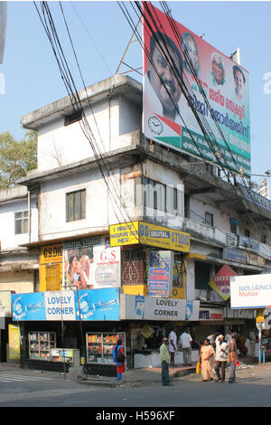 Tipicamente un malandato edificio con un enorme cartellone pubblicitario nella periferia di occupato di Kochi, una città nel sud dell'India. Foto Stock