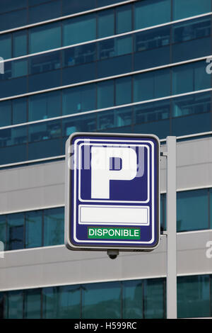 Parcheggio con signpost disponible testo e moderno edificio dello sfondo. In verticale Foto Stock