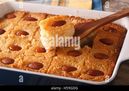 Torta Basbousa con mandorle macro in una teglia sul tavolo. Posizione orizzontale Foto Stock