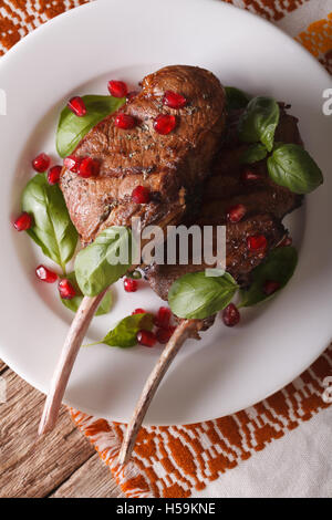 Bistecca di manzo con i semi di melograno e basilico close-up su una piastra verticale vista superiore Foto Stock