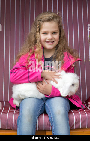 Giovane ragazza accarezzando coniglio alla fattoria per bambini Kirchdorf, Amburgo, Germania Foto Stock