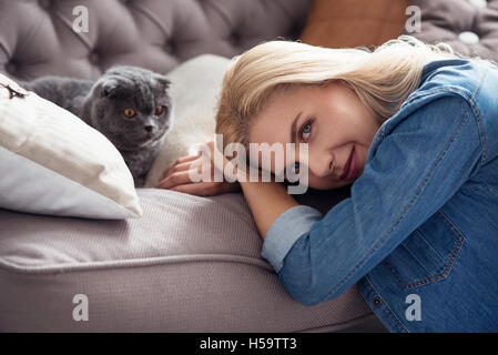 Dolce signora bionda con il suo gatto sul lettino Foto Stock