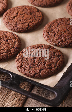 Appena sfornato biscotti al cioccolato su una placca da forno su una tavola di close-up verticale. Foto Stock
