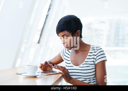 Pretty african imprenditrice utilizzando tablet amd avente pausa caffè in ufficio Foto Stock