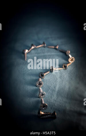 Small Twin-fast viti rivestito a forma di punto interrogativo su sfondo scuro Foto Stock Small Twin-fast viti rivestito a forma di punto interrogativo su sfondo scuro Foto Stock