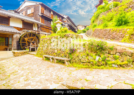 Case in legno e linea di waterwheel percorso di pietra su splendidamente restaurata la sezione storico di Edo-periodo Nakasendo, Magome Foto Stock