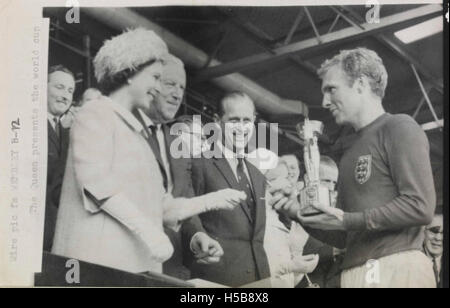 La regina Elisabetta II presenta il trofeo della Coppa del mondo FIFA 1966 al capitano inglese Bobby Moore. Questo momento si verificò dopo la vittoria dell'Inghilterra sulla Germania Ovest in finale, segnando un risultato storico nel calcio inglese. Foto Stock