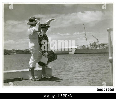 Le donne si spostano verso la HMAS Australia II o la HMAS Canberra i, due navi della Royal Australian Navy, durante il periodo 1945-1953, forse durante la partenza o il ritorno della marina. Foto Stock