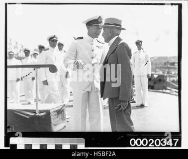 Il capitano John Collins della HMAS Sydney (II) è visto parlare con William Morris 'Billy' Hughes, ministro della Marina, il 10 febbraio 1941. Questa immagine cattura un momento significativo durante la seconda guerra mondiale nella storia navale dell'Australia. Foto Stock