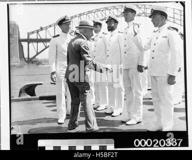 Questa immagine mostra il primo ministro australiano Billy Hughes che ispeziona l'equipaggio di HMAS Sydney (II) durante un evento navale. La foto include figure di rilievo come il capitano John Augustine Collins e LCDR e W Thruston, che illustrano un momento di leadership militare e di fidanzamento. Foto Stock