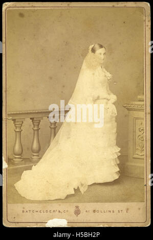 Una cartolina fotografica d'epoca con una donna in abito da sposa, che mostra la moda e le usanze che circondano i matrimoni in un periodo di tempo specifico. Foto Stock