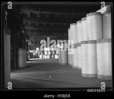 Vista interna del magazzino che mostra operai posizionamento rotoli di carta da giornale Foto Stock