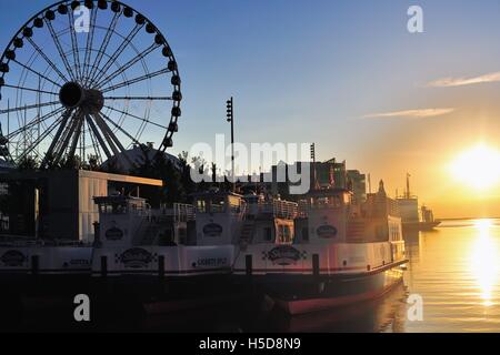 Il sole sorgere riflettendo sull'acqua taxi legato lungo Chicago il Navy Pier su una tarda mattina d'estate. Chicago, Illinois, Stati Uniti d'America. Foto Stock